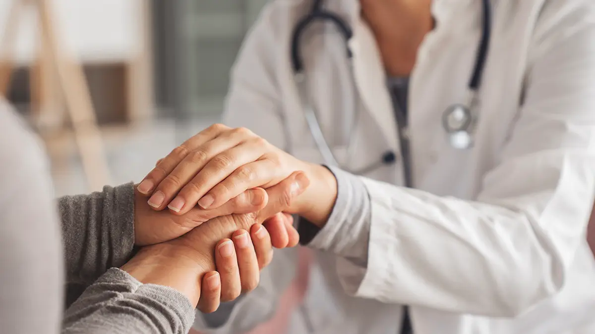 Close up of physician holding patient's hands